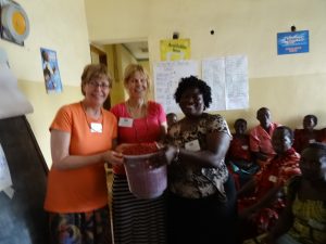 Carolyn and Karon standing with Fenny in front of the room of women, holding a large basket of peanuts