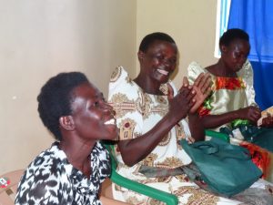 Three women smile and clap as they discuss their new microloan.