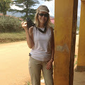 Woman standing wearing sunglasses holding a camera.