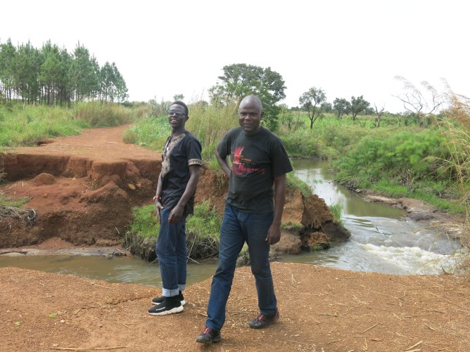 Two men standing near washed out road.