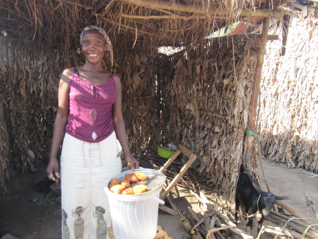 Woman standing in hut, smiling.